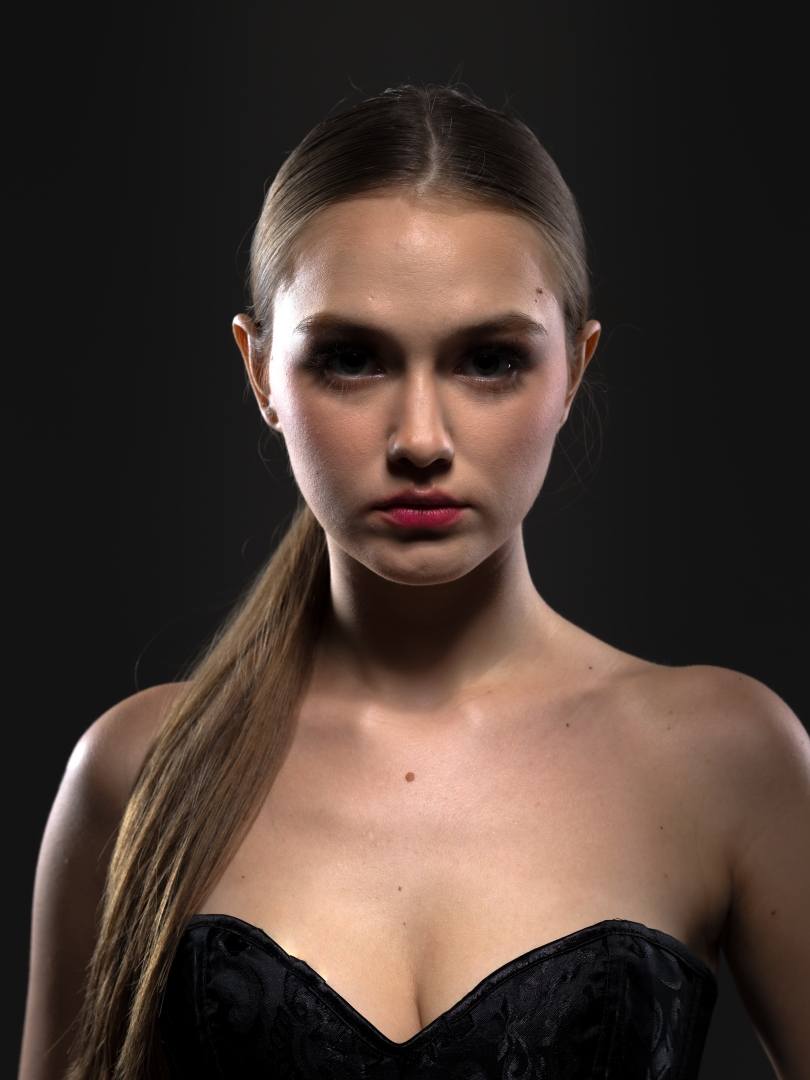 Model in a black corset with a long ponytail, low key studio light