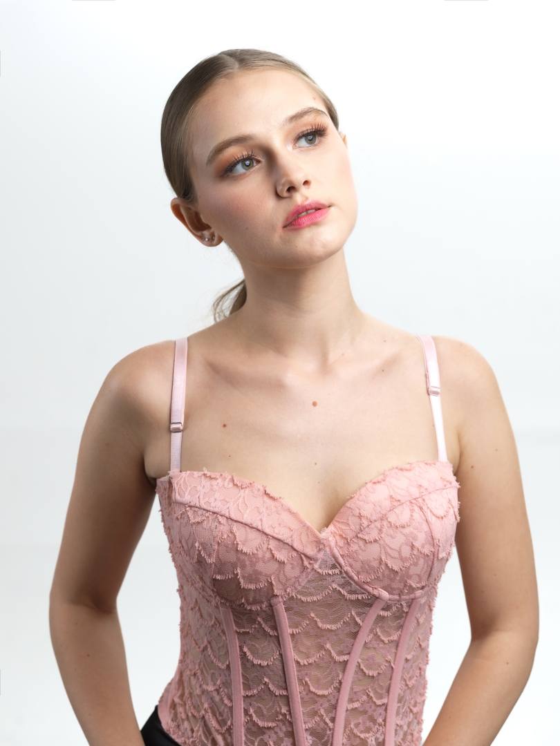Model in a pink lace corset against a white background