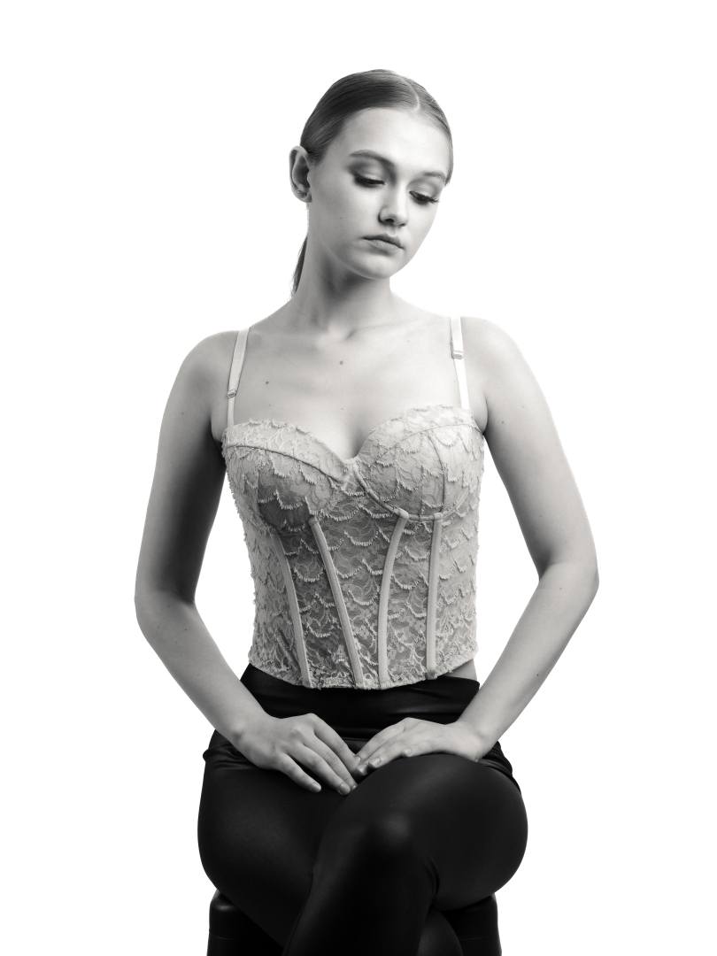 Black and white portrait of a model in a lace corset, seated