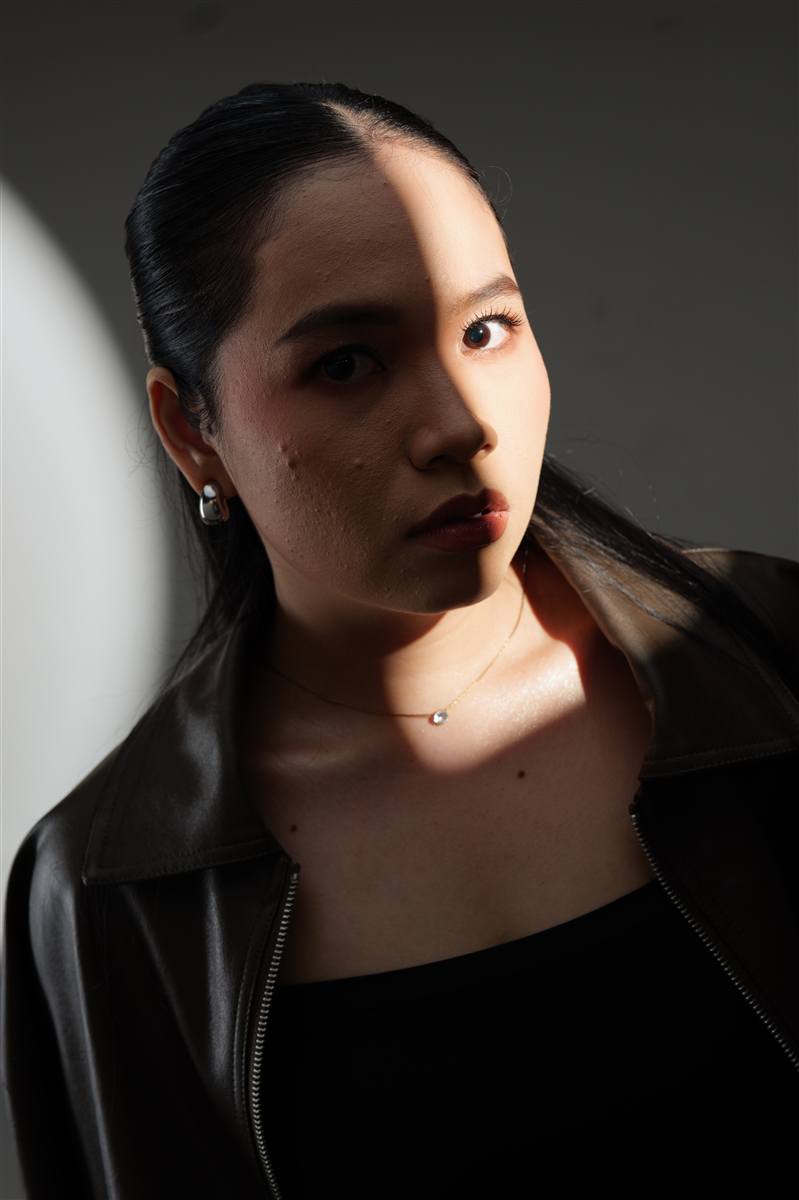 Woman in a leather jacket lit by a hard beam of light