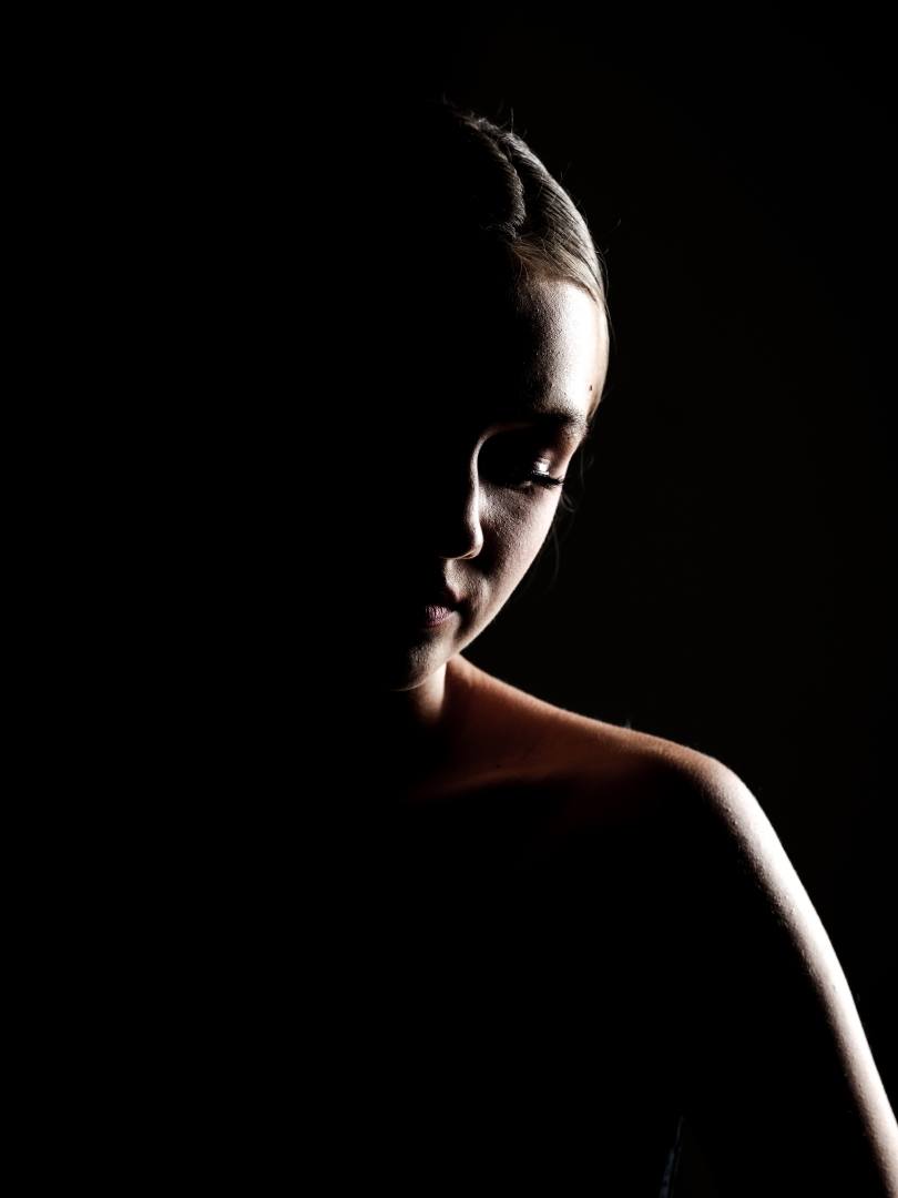 Profile of a woman lit only along her edge against black