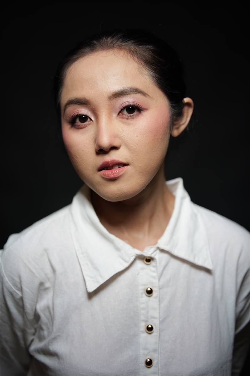 Studio portrait of a woman in a white shirt against a dark background