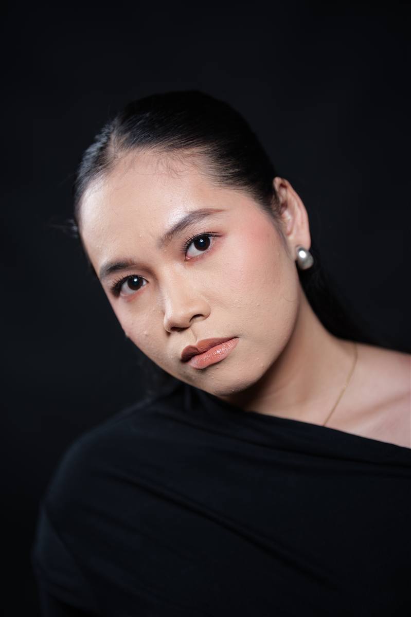 Woman in a black off-shoulder top against a black background