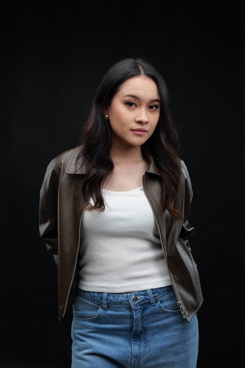 Woman in a leather jacket and white tank top, dark studio